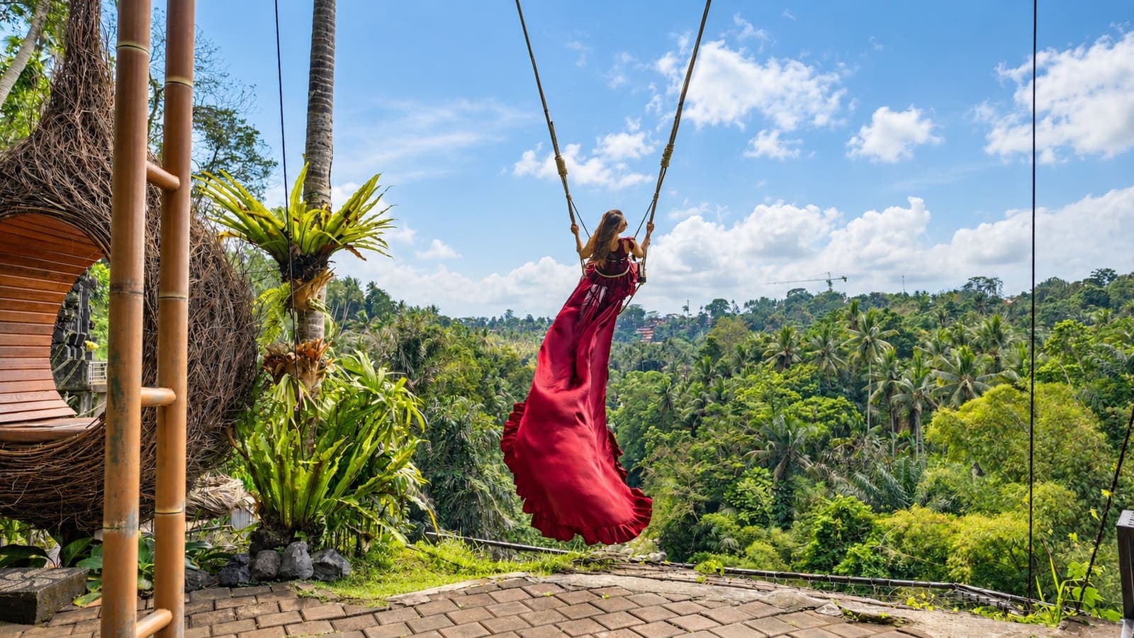 Traveller in a red dress on a jungle swing
