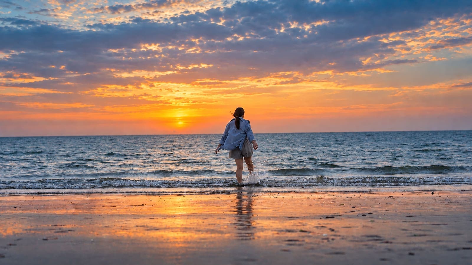 Traveller walking into the sea at sunset